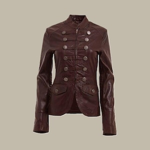 May include: A dark brown leather jacket with a high collar and decorative buttons. The jacket features a zip closure and two small pockets. The sleeves are long and fitted, and the jacket has a tailored fit. The jacket is a classic style.
