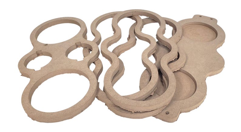 May include: A collection of unfinished, light brown wooden cutouts in various shapes. The shapes include a figure eight with holes, wavy lines, and a tray with circular cutouts. These craft supplies are ready for painting or other customization.
