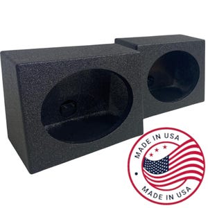 May include: Two black speaker boxes with oval openings. The boxes have a textured finish and are side by side. A red, white, and blue "Made in USA" sticker is in the lower right corner.
