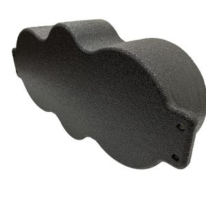May include: A textured, dark gray object with a unique, cloud-like shape. The object has a rounded, cylindrical end and a series of curved indentations along its side. The surface appears to be matte and non-reflective.