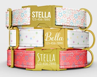 May include: Three dog collars stacked on top of each other. The top collar is white with colorful stars, the middle collar is white with pastel stars, and the bottom collar is red with blue and orange stars. Each collar has a gold buckle with a name and phone number.