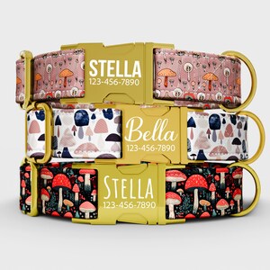 May include: Three dog collars with mushroom designs. The top collar is pink with orange and white mushrooms, the middle collar is white with blue and pink mushrooms, and the bottom collar is black with red mushrooms. Each collar has a gold buckle with a name and phone number.