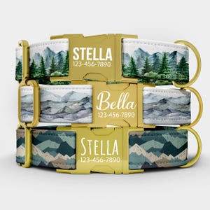 May include: Three dog collars stacked on top of each other. The collars have gold-colored buckles and D-rings. The top collar has a mountain and forest design. The middle collar has a mountain design. The bottom collar has a mountain design. Each collar has a name and phone number.