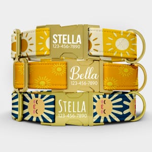 May include: Three personalized dog collars stacked on top of each other. The top collar is yellow and cream with a sun pattern, the middle is orange with a sun pattern, and the bottom is navy blue with a sun face design. Each collar has a name and phone number.