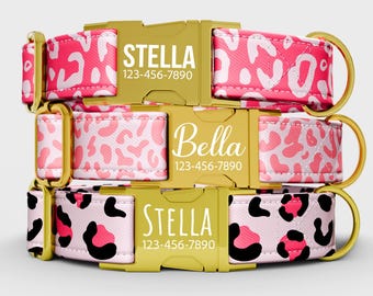 May include: Three personalized dog collars with gold-colored buckles. The collars feature a pink and white leopard print design. One collar is labeled "Stella" with a phone number, and another is labeled "Bella" with a phone number.