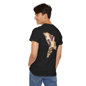 May include: A black short-sleeved t-shirt featuring a map-shaped graphic on the back. The graphic contains illustrations of a traditional clay pitcher, a cluster of purple grapes, stalks of wheat, and a small rustic house with a thatched roof.