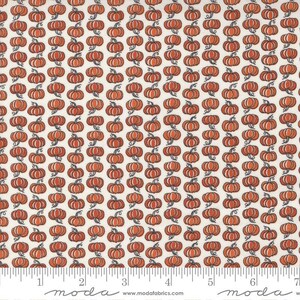 May include: White fabric with a repeating pattern of orange pumpkins with stems and leaves. The fabric is measured with a ruler in inches.