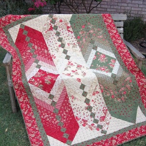 Pode incluir: Um cobertor vermelho, branco e verde com um padrão geométrico. O cobertor é feito de vários tecidos florais e é acolchoado com um padrão de diamante.