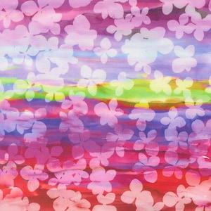 May include: A fabric pattern featuring a vibrant, horizontal watercolor-style gradient background in shades of pink, purple, blue, green, and yellow, overlaid with a repeating, semi-transparent white silhouette of small, four-petaled flowers.