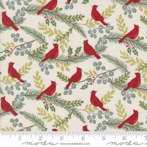 May include: Cream fabric featuring a repeating pattern of red cardinal birds on branches with green and grey leaves and holly berries. A ruler is along the bottom edge of the fabric.