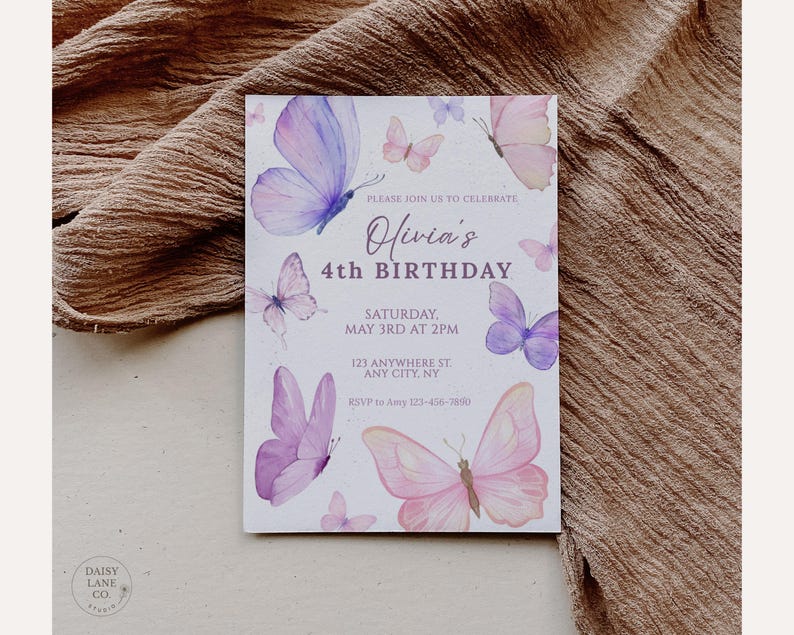 May include: A rectangular invitation card with watercolor butterflies in shades of purple and pink. The text reads "Olivia's 4th Birthday" with event details. The card is set against a textured, neutral-toned fabric.