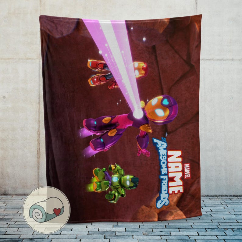Op de afbeelding: Een bruine deken met een kleurrijke cartoonillustratie van vliegende figuren, waaronder een paars en geel figuur dat een roze straal uitzendt. De deken heeft de tekst "NAME" en "Awesome Friends" met het Marvel-logo.