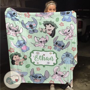 Puede incluir: Una manta verde claro con personajes de dibujos animados, incluyendo Stitch y Lilo, con un nombre personalizado, Ethan, en un marco decorativo. La manta tiene un patr&oacute;n repetido de los personajes y acentos florales.