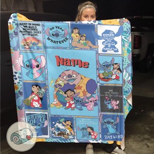May include: A blue, pink, and white throw blanket featuring various images of Stitch and Lilo from the Disney movie. The blanket has text that reads "Hand in Hand We Build Memories Painting Skies With Love" and "Stay Weird".