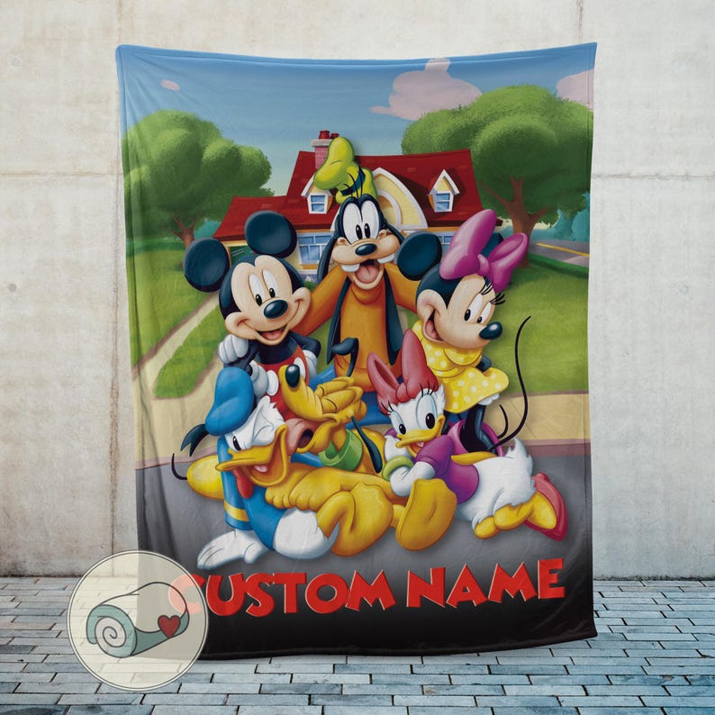 K&ouml;nnte beinhalten: Eine weiche Decke mit Mickey Mouse, Minnie Mouse, Donald Duck, Daisy Duck, Goofy und Pluto vor einem Haus. Die Decke hat einen blauen Himmelshintergrund und die Worte "CUSTOM NAME" in Rot.