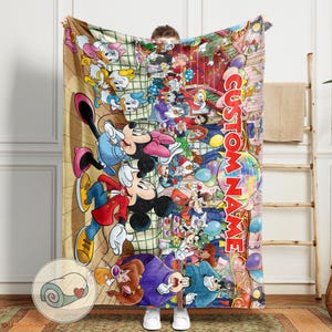 Pu&ograve; includere: Una grande coperta colorata con un collage di personaggi dei cartoni animati, tra cui Topolino e Minnie, Paperino e Pippo. La coperta ha uno sfondo marrone con le parole "CUSTOM NAME" in un design verticale. Una coperta arrotolata con un cuore &egrave; nell'angolo.
