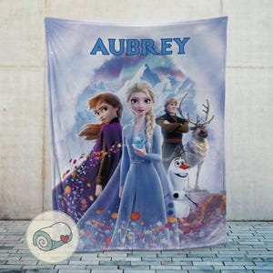 May include: A white ceramic mug with a black handle and the text "But First, Coffee" in a bold, black font. The mug is set against a blurred background, suggesting a cozy setting.