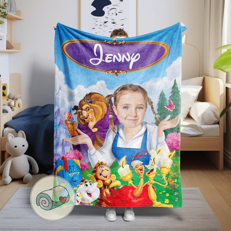 Peut inclure: Une couverture bleue personnalis&eacute;e avec un portrait d'une fille avec des couettes, entour&eacute;e de personnages de La Belle et la B&ecirc;te. La couverture porte une banni&egrave;re violette avec le nom "Jenny" en &eacute;criture blanche et un dessin de couverture roul&eacute;e.