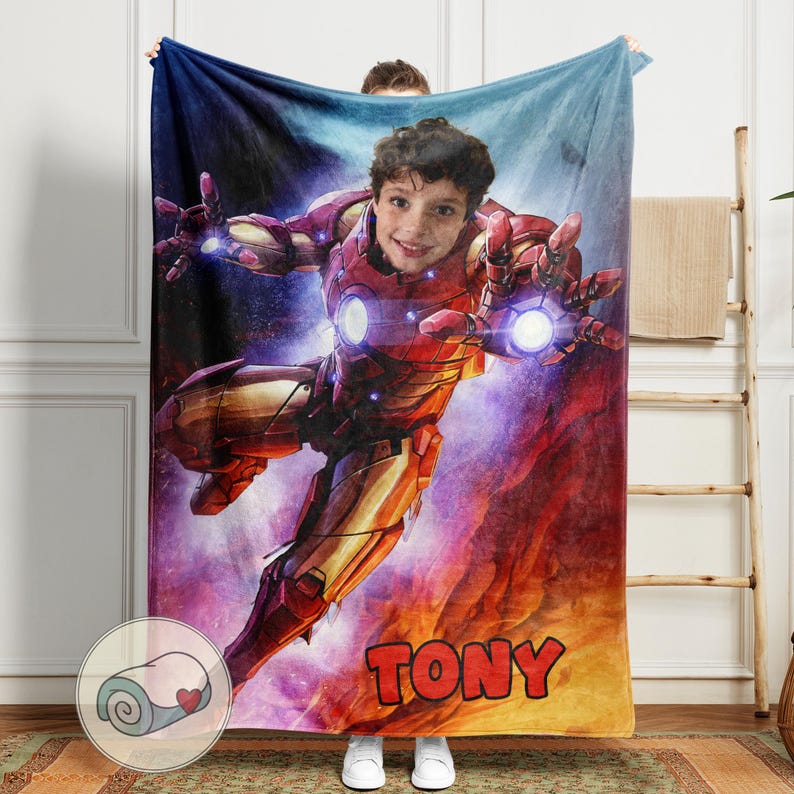 Peut inclure: Une couverture personnalis&eacute;e avec le visage d'un enfant superpos&eacute; &agrave; un design de costume d'Iron Man. La couverture est principalement rouge et or, avec le nom "TONY" en grandes lettres orange en bas. Le fond a un th&egrave;me cosmique.