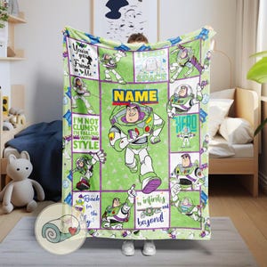 May include: A green and purple Buzz Lightyear blanket featuring the character in various poses. The blanket has a grid design with phrases like "I need space" and "to infinity and beyond!" The blanket is made of soft material.