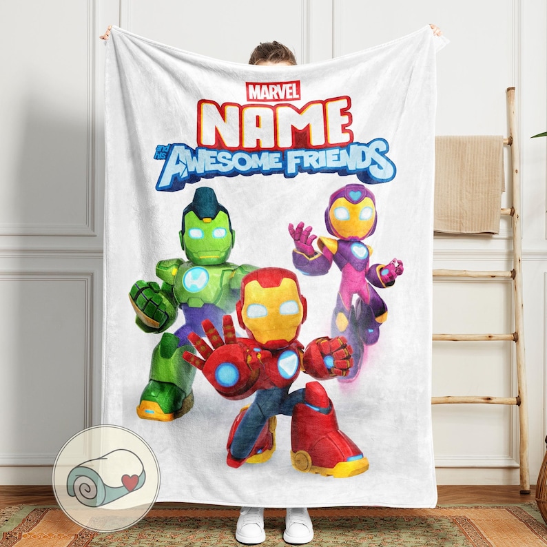 Op de afbeelding: Witte Marvel-deken met de tekst "NAME Awesome Friends" in rood en blauw. De deken toont drie stripfiguren in rood, groen en paars. Het Marvel-logo staat bovenaan.