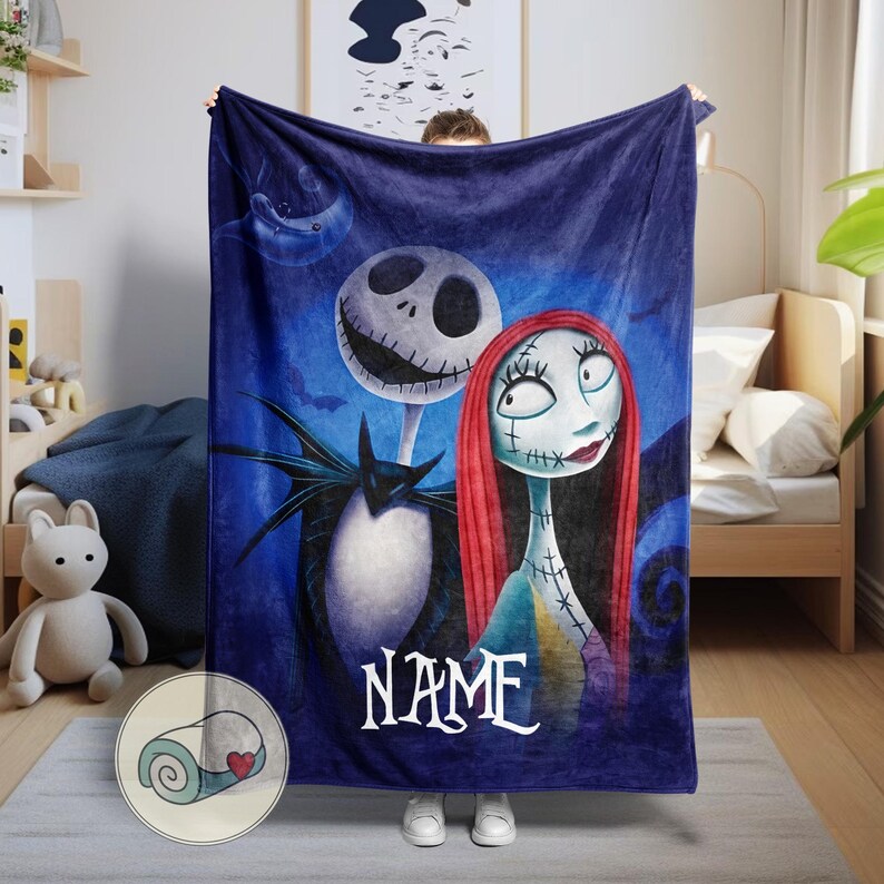 May include: A dark blue blanket featuring Jack Skellington and Sally from The Nightmare Before Christmas. The blanket has a personalized name in white script at the bottom. The characters are set against a dark blue background with a moon and bats.