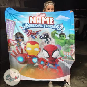 May include: A blue Marvel blanket featuring Iron Man, Spider-Man, and the Hulk, with the text "NAME Awesome Friends 4". The blanket has a cartoon design with a cityscape background and the Marvel logo.