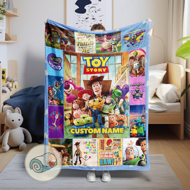 May include: A blue fleece blanket with a collage of images from the film "Toy Story." The blanket features characters like Woody and Buzz Lightyear, with the words "Toy Story" and "Custom Name" displayed. The blanket is a soft, cosy item.