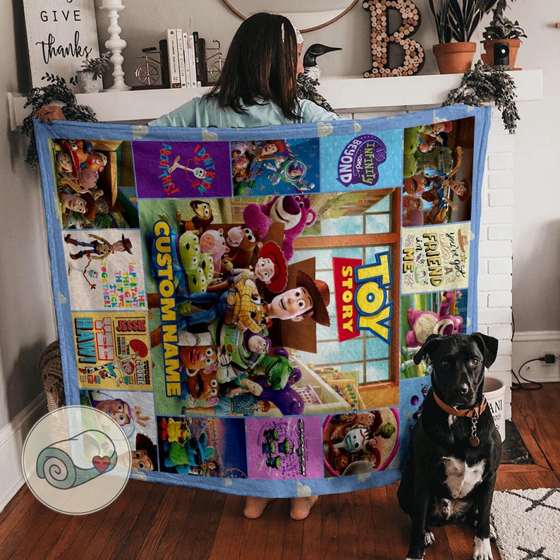 May include: A vibrant Toy Story blanket with a blue border. The blanket showcases characters like Woody and Buzz Lightyear. The words "Toy Story" and "Custom Name" are displayed. The blanket is likely made of soft material.
