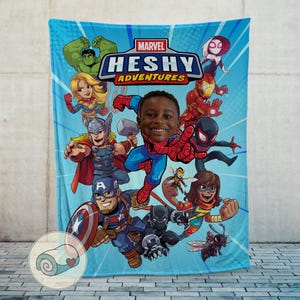 Peut inclure: Une couverture bleu clair sur le th&egrave;me de Marvel, avec divers super-h&eacute;ros, dont Spider-Man, Captain America et Thor. La couverture porte le texte "HESHY ADVENTURES" et une photo d'un enfant souriant. Le logo Marvel est en haut.