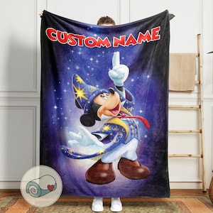 Op de afbeelding: Een zachte deken met een cartoonafbeelding van Mickey Mouse als tovenaar op een sterrenblauwe achtergrond. De tekst "CUSTOM NAME" staat in het rood. Deze deken is ontworpen voor comfort en warmte.