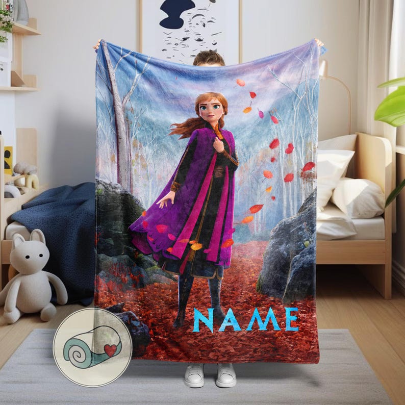 Pode incluir: Uma manta macia com uma ilustra&ccedil;&atilde;o vibrante de uma personagem de um filme de anima&ccedil;&atilde;o popular. O design apresenta uma personagem com uma roupa roxa e preta, num cen&aacute;rio de floresta com folhas a cair. A palavra "NAME" &eacute; exibida em azul.