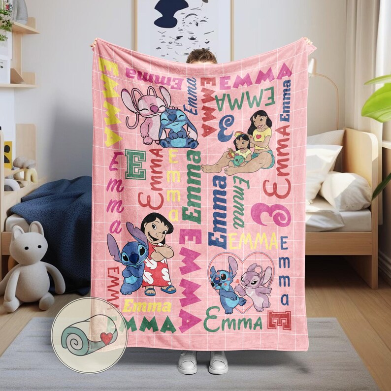 May include: A pink blanket featuring cartoon characters and the name "Emma" in various fonts and colors. The blanket has a grid pattern and includes images of characters from a popular animated movie.