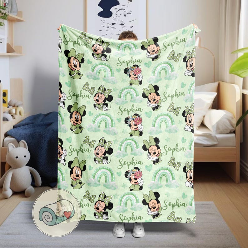 K&ouml;nnte beinhalten: Eine hellgr&uuml;ne Decke mit einem sich wiederholenden Muster aus Minnie Mouse, Regenbogen und Schmetterlingen. Der Name "Sophia" ist auf dem Design aufgedruckt. Die Decke ist aus weichem Material, ideal f&uuml;r ein Kinderzimmer.
