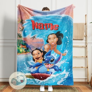 May include: A blue blanket featuring a cartoon image of Lilo, Stitch, and Nani surfing a wave. The word "Name" is in red across the top. The blanket has a rolled-up image of the blanket with a heart on it.