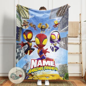 May include: A plush blanket featuring a colorful illustration of Spider-Man and his Amazing Friends against a cityscape backdrop. The blanket has the text "NAME" and "The Amazing Friends" in a bold font. The blanket is soft and cozy.