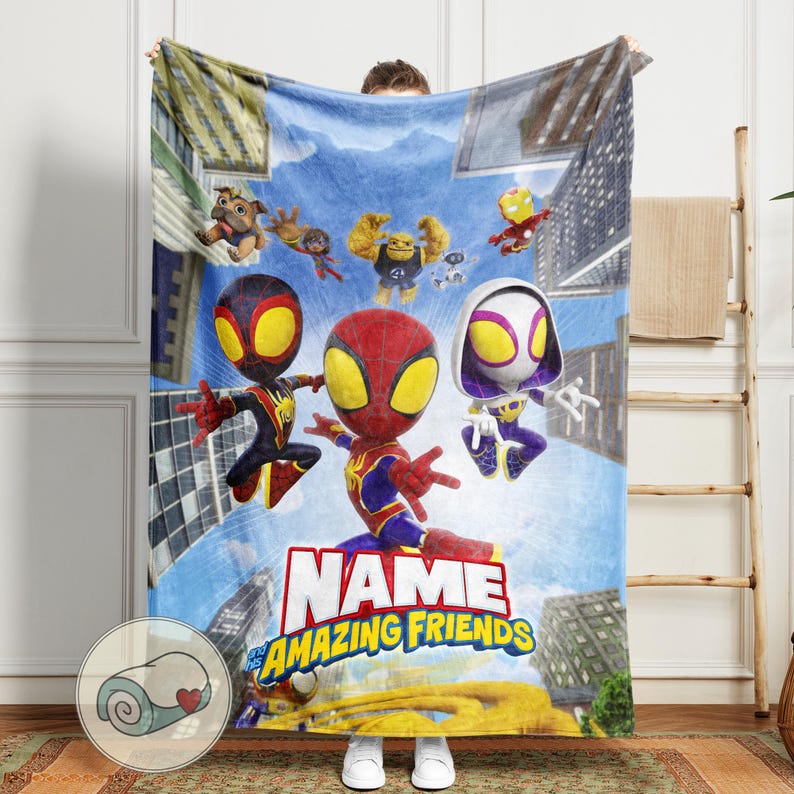 May include: A plush blanket featuring a colorful illustration of Spider-Man and his Amazing Friends against a cityscape backdrop. The blanket has the text "NAME" and "The Amazing Friends" in a bold font. The blanket is soft and cozy.