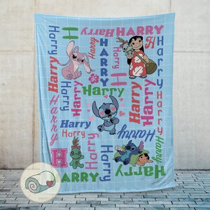 K&ouml;nnte beinhalten: Eine hellblaue Decke mit Zeichentrickfiguren und dem Namen "Harry" in verschiedenen Farben. Die Decke hat ein Gittermuster und zeigt Bilder von Stitch und Lilo.