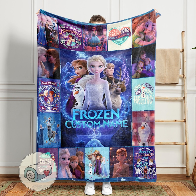 Puede incluir: Una manta azul y morada con tem&aacute;tica de Frozen con Elsa, Anna, Olaf y Kristoff. La manta tiene varias im&aacute;genes y texto de la pel&iacute;cula, incluyendo "Frozen" y "Custom Name". La manta se muestra sobre un fondo claro.