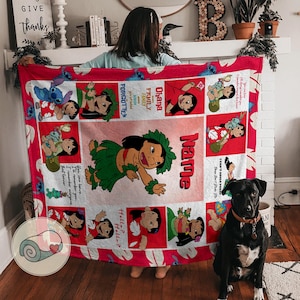 May include: A red and white blanket featuring cartoon images of Lilo and Stitch. The blanket has a red border and includes the text "Ohana Family" and "I Can't Adult Today". The blanket is held up by a person.