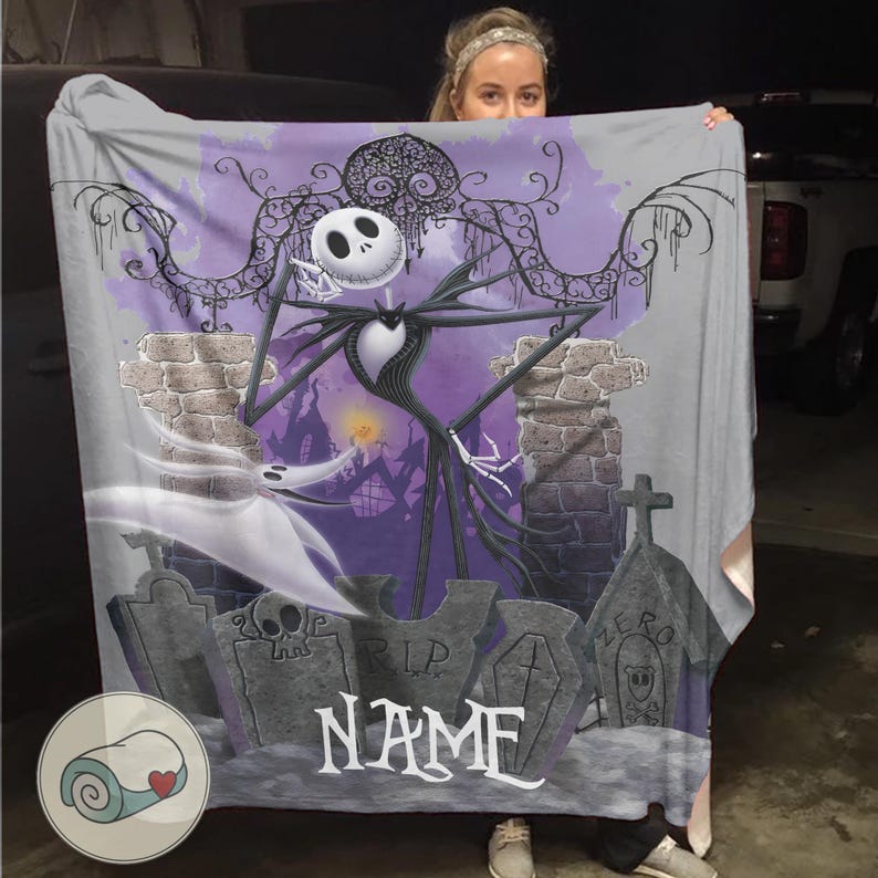 May include: A gray blanket featuring a design of Jack Skellington from The Nightmare Before Christmas. The design includes a graveyard scene with tombstones, the character Zero, and the word "NAME". The blanket has a purple and gray color scheme.