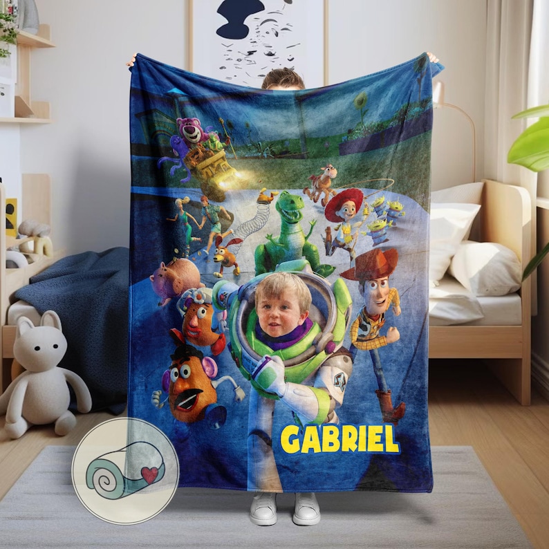 May include: A blue blanket featuring characters from the animated film Toy Story, including Buzz Lightyear, Woody, and Rex. The blanket has a personalized name, "GABRIEL," in yellow block letters. The blanket is made of soft material.