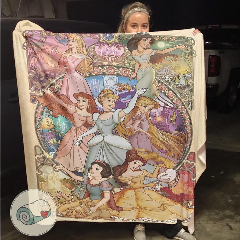 Peut inclure: Une couverture cr&egrave;me avec une illustration color&eacute;e de princesses Disney. Le motif comprend des personnages comme Cendrillon, Ariel et Belle, sur un fond d&eacute;coratif floral et architectural. Le mot "Princess" est visible.
