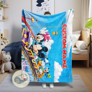 May include: A blue blanket featuring Mickey Mouse, Minnie Mouse, Donald Duck, and Goofy on a roller coaster against a blue sky background. The blanket has the text "CUSTOM NAME" in red. The blanket is soft and cozy.