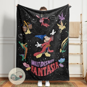 May include: Black blanket with characters from Disney's Fantasia, including Mickey Mouse as the Sorcerer's Apprentice, and the film's title. The blanket has a rolled-up image in the corner. The blanket is held up by a person.