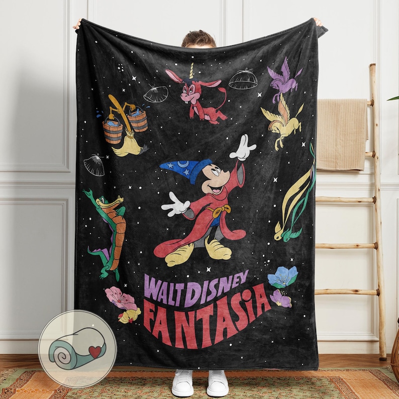 May include: Black blanket with characters from Disney's Fantasia, including Mickey Mouse as the Sorcerer's Apprentice, and the film's title. The blanket has a rolled-up image in the corner. The blanket is held up by a person.