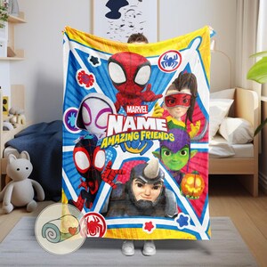 May include: A Marvel "Amazing Friends" blanket featuring Spider-Man and other characters. The blanket has a blue and yellow background with character illustrations and the text "Marvel Name Amazing Friends".