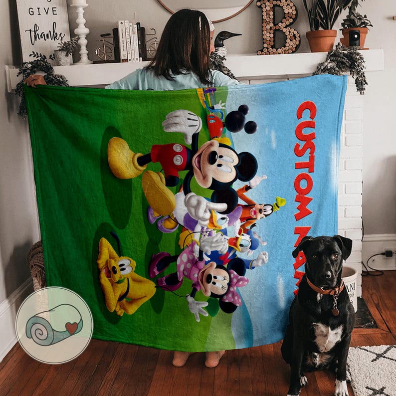 Pu&ograve; includere: Una grande coperta rettangolare con un vivace design a cartoni animati con i personaggi di Topolino, Minnie, Paperino e Pluto. La coperta ha uno sfondo verde e blu con il testo "CUSTOM NAME".