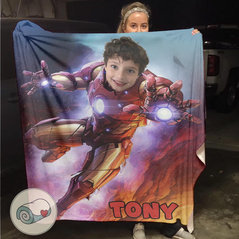 Peut inclure: Une couverture personnalis&eacute;e avec le visage d'un enfant superpos&eacute; &agrave; un costume d'Iron Man. La couverture est principalement rouge et or, avec le nom "TONY" en grandes lettres en bas. Le fond pr&eacute;sente un design cosmique et flamboyant.