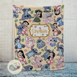 Pu&ograve; includere: Una coperta beige con un motivo ripetuto del personaggio Stitch del film Disney Lilo & Stitch. La coperta ha un nome personalizzato, "Sophia", in una cornice decorativa. La coperta &egrave; ricoperta di illustrazioni di Stitch e Lilo.